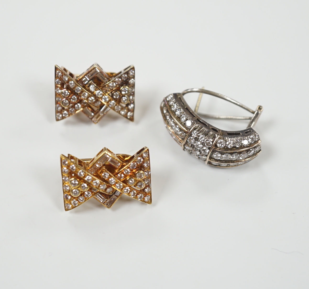 A pair of yellow metal and diamond chip cluster set earrings, of stylised bow form, 19mm and one other demi-lune shaped white metal and diamond cluster set earring, gross weight 17.7 grams.